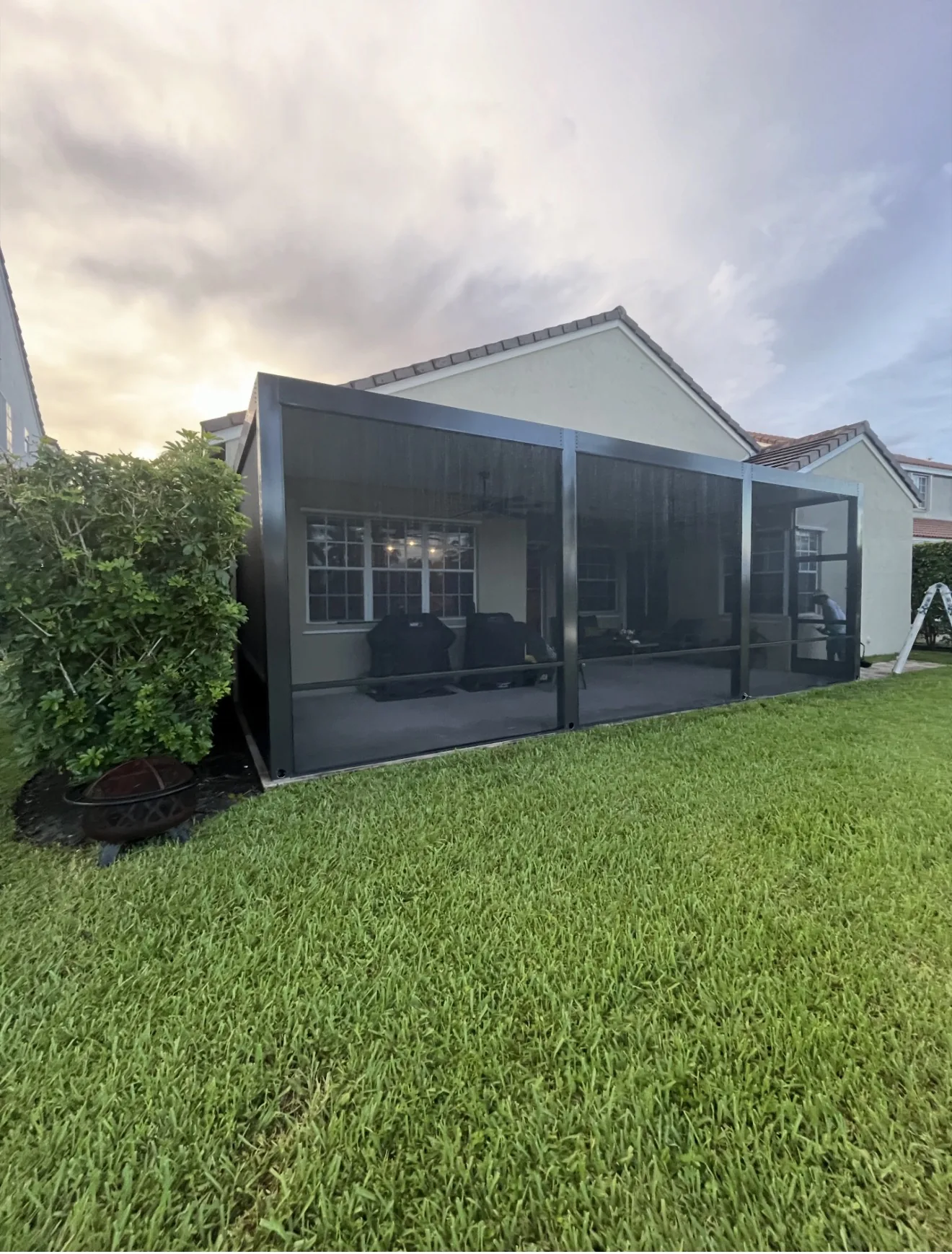 Dark framed screen enclosure around a covered backyard patio.