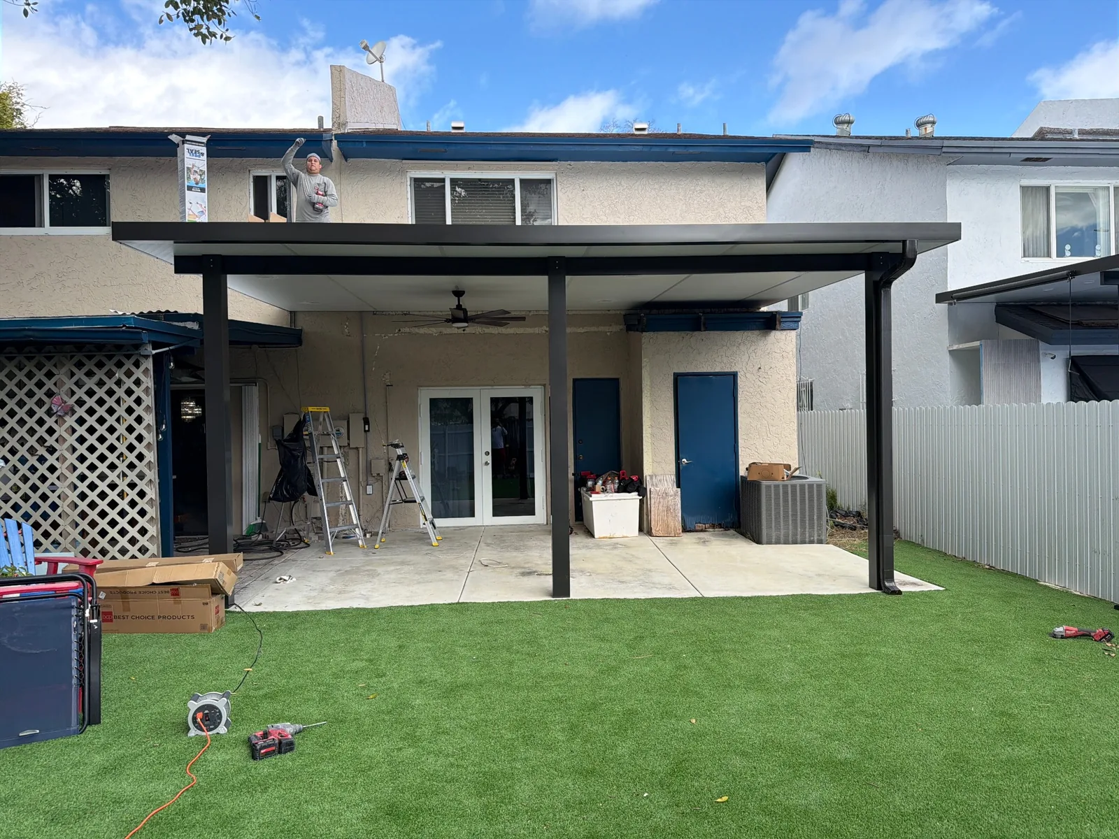 Finished black pergola covering a townhouse patio and backyard seating area.
